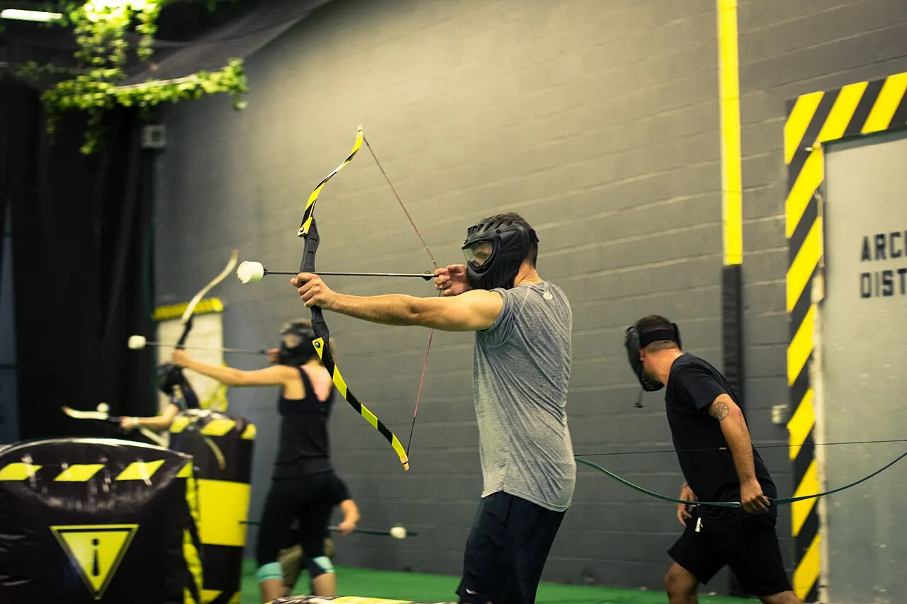 Joueur casqué qui bande son arc à flèches mousse pendant une partie d'Archery Game