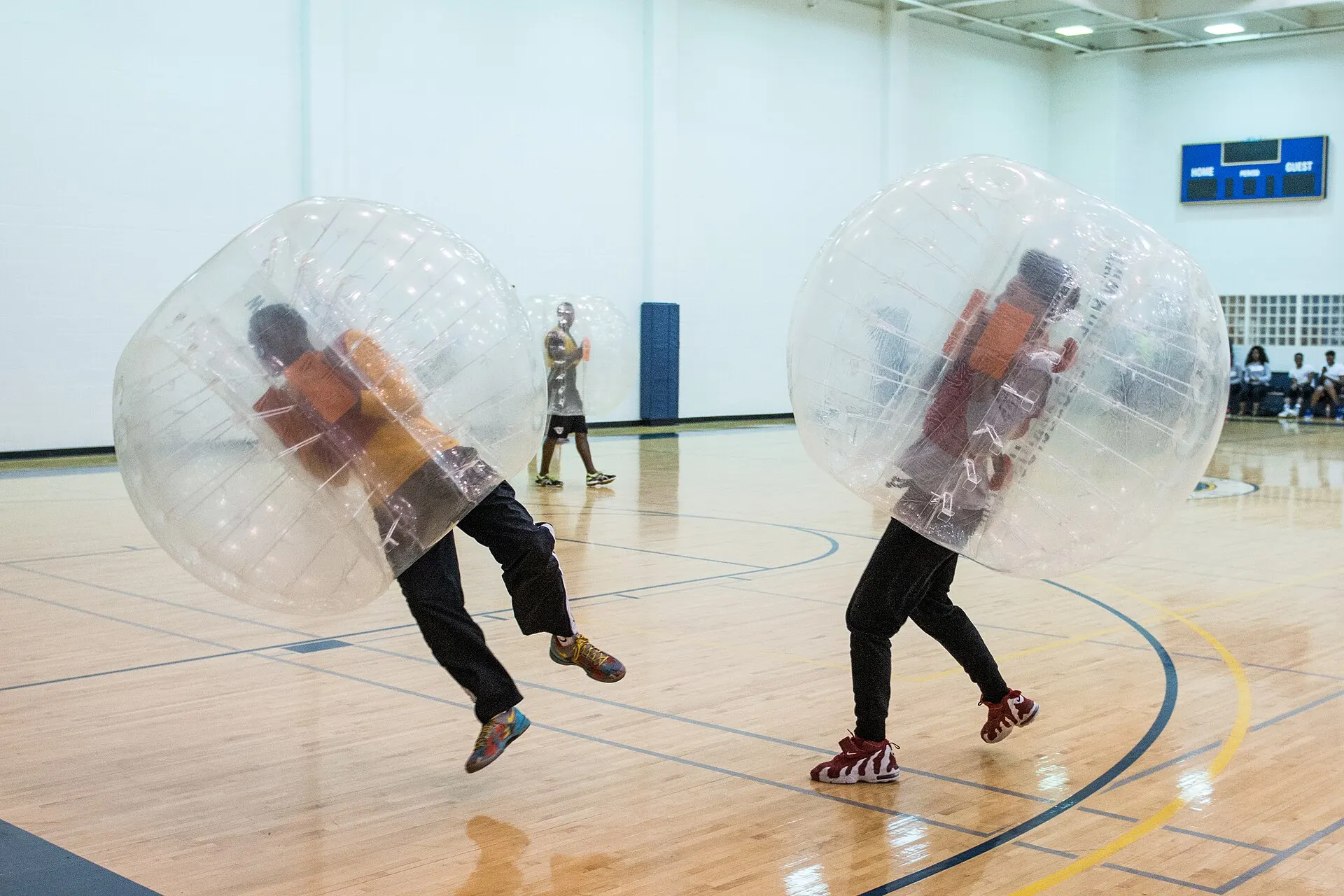 Deux joueurs en bulle se percutent sur un terrain de sport en salle